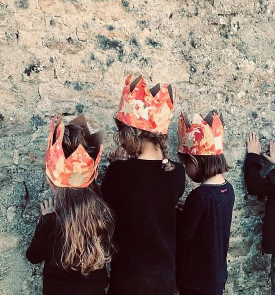 enfants de 6 à 8 ans tournés contre un mur, les mains sur le mur, une couronne colorée de taches oranges sur leurs têtes